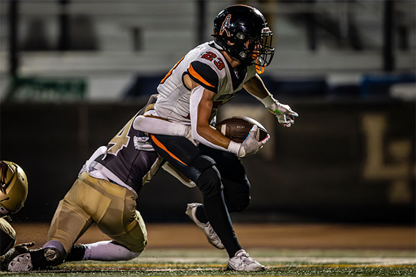 Micah Riola (#23) fights to stay off the ground.